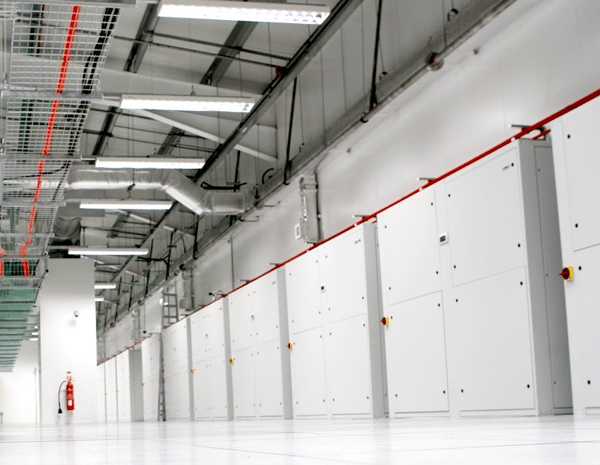Long technical corridor lined with white access panels and overhead services
