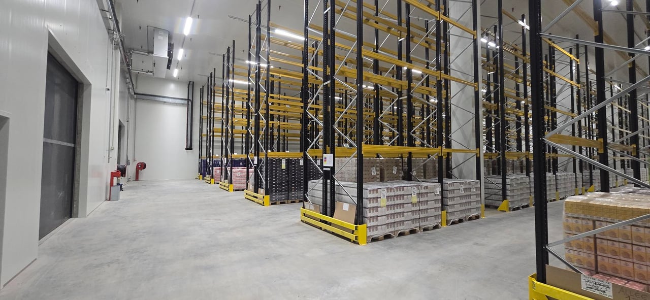 Allée d'entrepôt frigorifique entre des racks à palettes chargés