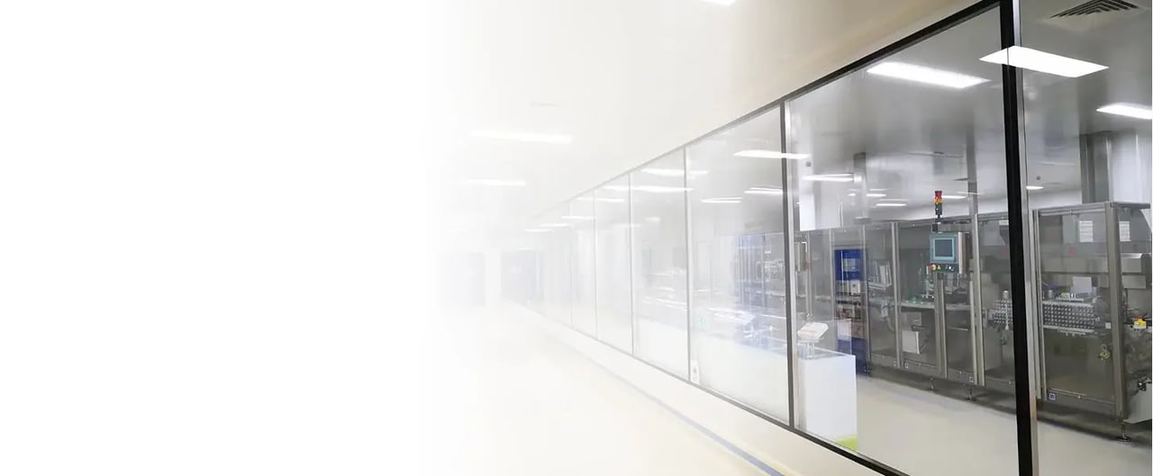 Corredor de sala limpa com divisória envidraçada e equipamento de produção atrás