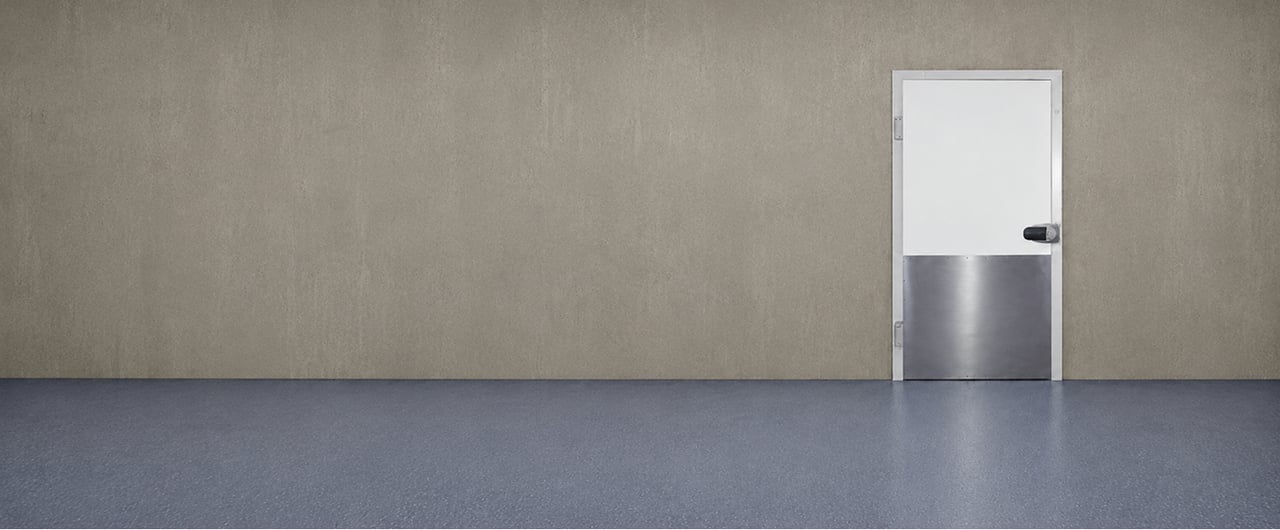 White door with a stainless steel kick plate in a grey wall