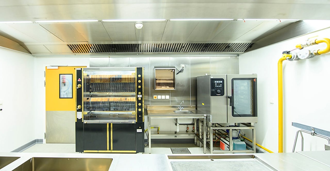Professional kitchen with rotisserie ovens and an extraction canopy